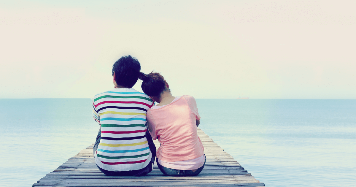 桟橋でカップルが肩を寄り添い海を眺めている