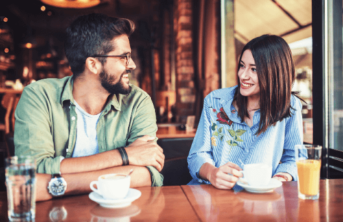  既婚男性とコーヒーを飲んでいる女性。楽しそうに2人とも微笑んでいる